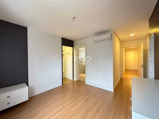 Hall de entrada com piso de madeira clara e paredes brancas.