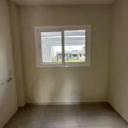 Foto interna de um cômodo com parede clara e janela.