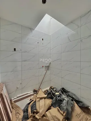 Parede interna com revestimento de mármore e teto inclinado em obra.
