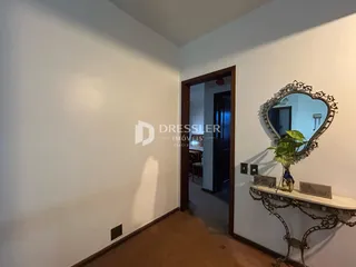 Hall de entrada com paredes brancas e piso de madeira.