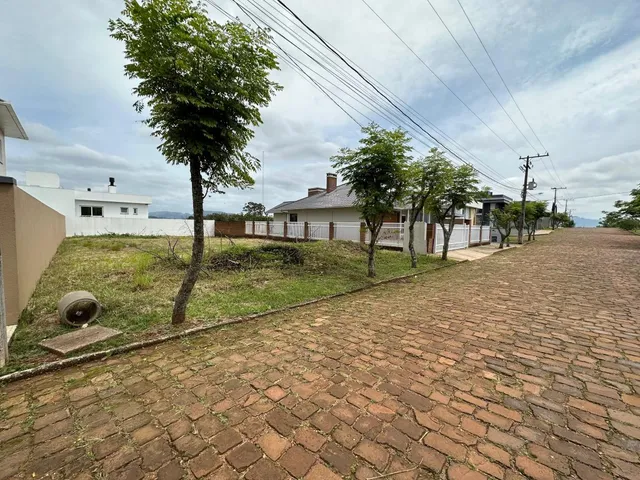 Foto da área externa com piso de tijolos e grama.