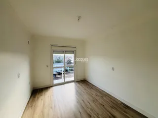 Vista interna de uma sala com piso de madeira clara e porta de vidro.
