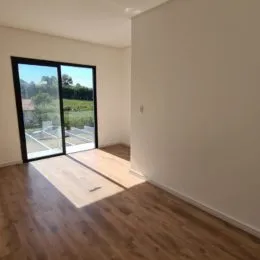 Sala de estar com piso de madeira e porta de vidro que dá para o exterior.