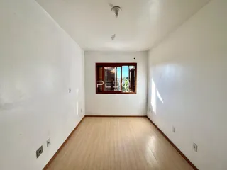 Vista de um corredor interno com paredes brancas e piso de madeira clara.