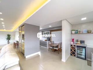 Uma sala de estar ampla com sofá e área de jantar em um apartamento.