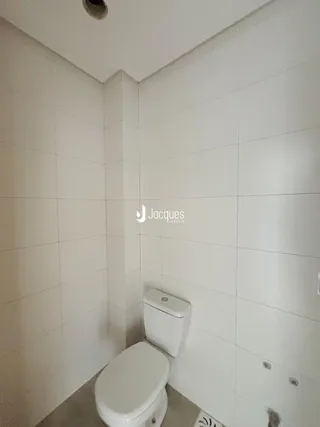 Foto interna de um banheiro com paredes brancas e azulejos.