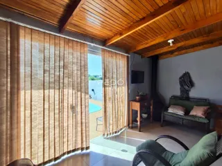 Interior de uma sala com teto de madeira e portas de vidro que dão acesso a uma área externa.