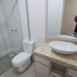 Foto de um banheiro com box de vidro e vaso sanitário branco.