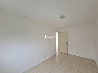 Um corredor interno com piso de cerâmica e paredes brancas.