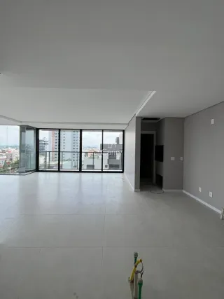 Ambiente interno amplo com piso claro e grandes janelas que oferecem vista.
