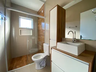 Banheiro com box de vidro e bancada de madeira.
