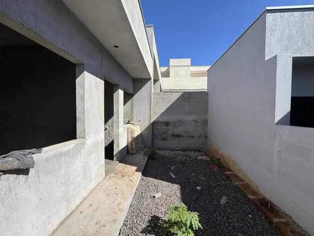 Vista externa de um pátio com piso de cascalho entre edifícios.