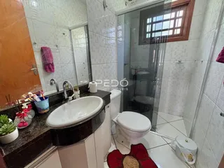 Foto interna de um banheiro com azulejos brancos e box de vidro.