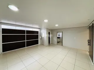 Interior de uma sala ampla com piso de cerâmica e porta de garagem.