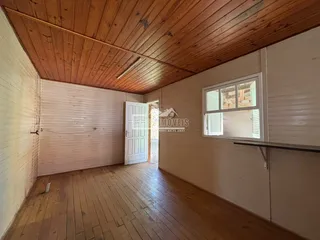 Interior de uma sala com piso e teto de madeira clara.