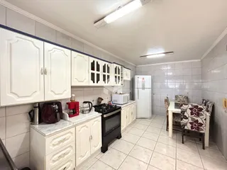 Cozinha com armários brancos e piso claro em imóvel no Brasil.