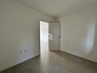 Hall de entrada com piso de cerâmica e porta branca.