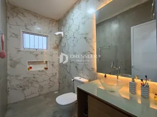 Foto de um banheiro com revestimento de mármore branco e louças sanitárias modernas.