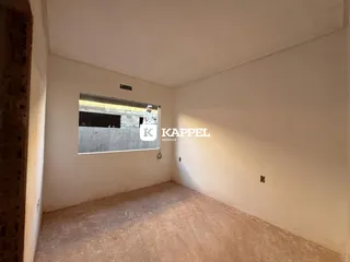 Foto de um cômodo interno com paredes brancas e piso de concreto aparente.