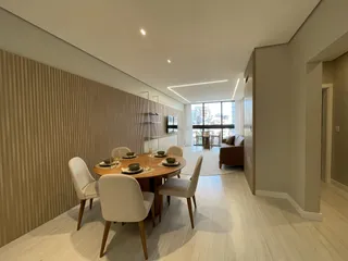 Mesa de jantar com cadeiras brancas em um ambiente moderno.