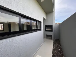 Fachada externa de uma parede branca com janelas escuras em uma residência.