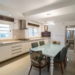 Vista interna de uma cozinha com armários claros e bancadas.
