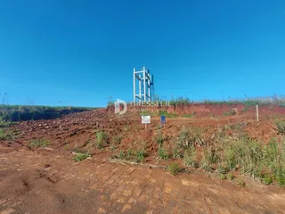 Paisagem de terra vermelha com uma estrutura metálica no fundo sob um céu azul.