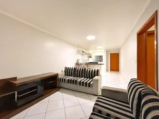 Sala de estar com sofá listrado e piso de cerâmica claro.