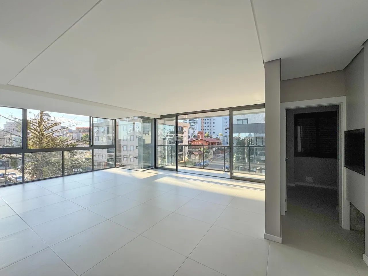 Sala de estar ampla com grandes janelas que oferecem vista da cidade.
