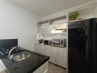 Vista da cozinha com bancada de granito e armários brancos.