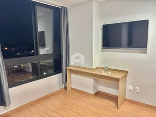 Sala de estar com vista noturna através de grandes janelas.