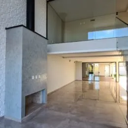 Hall de entrada com guarda-corpo de vidro e piso claro.