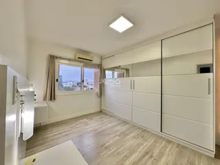 Ambiente interno de um imóvel com piso de madeira clara e armários brancos.