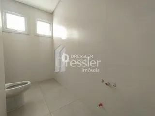 Foto de um banheiro interno com paredes brancas e janela.