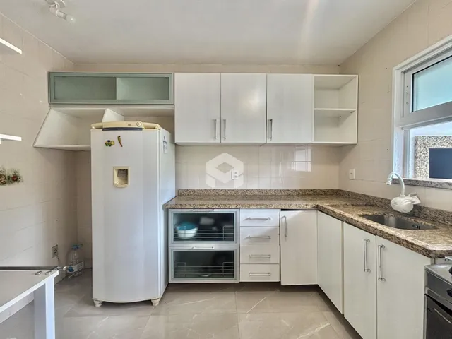 Foto de uma cozinha com armários brancos e bancada de granito.