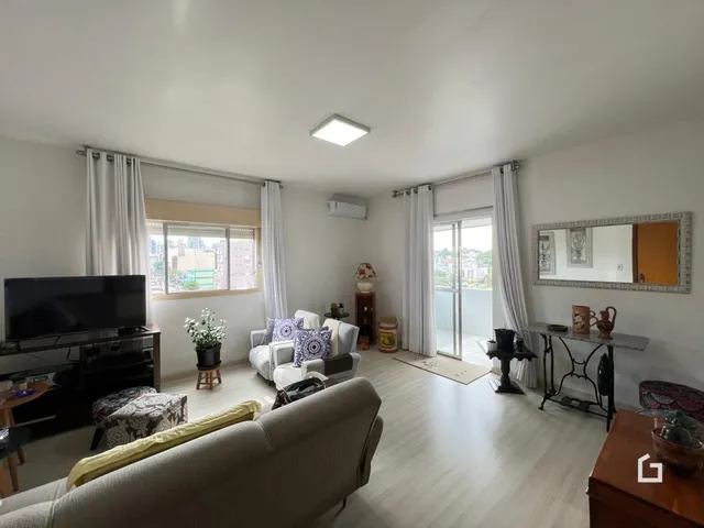 Sala de estar com piso de madeira clara e grandes janelas.