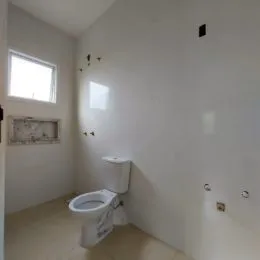 Hall de entrada com janela e vaso sanitário em uma residência.