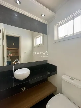 Foto de um banheiro moderno com bancada escura e louças brancas.