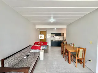 Foto de uma sala de estar e jantar com sofá e mesa de madeira em um apartamento.