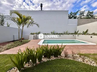 Foto externa mostrando uma piscina e área de jardim com palmeiras.