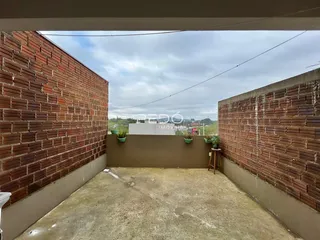 Vista externa de um pátio com paredes de tijolo.