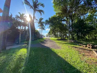 Vista externa de um terreno com gramado e vegetação ao redor.