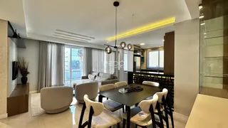 Sala de estar com mesa de jantar e grandes janelas em um imóvel no Brasil.