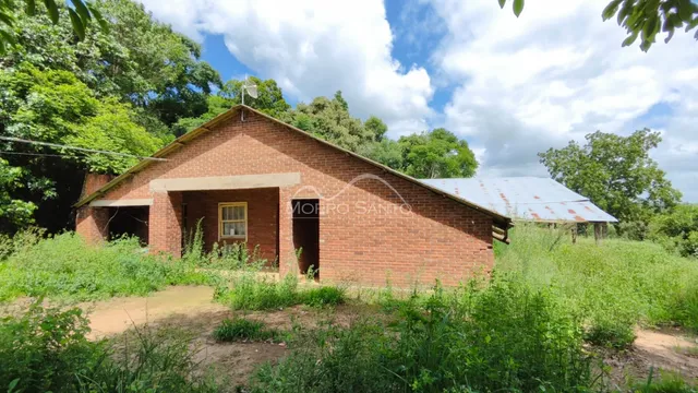 Fachada de uma casa de tijolos vermelhos em Lajeado, Brasil, cercada por vegetação densa.