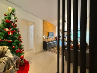 Ambiente interno com árvore de Natal decorada e passagem para outra sala.