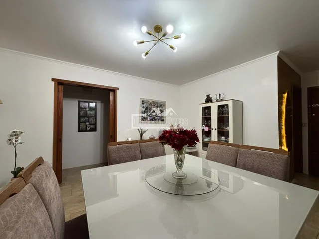 Sala de jantar com mesa branca e estofados em ambiente claro.