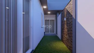 Corredor interno com parede de tijolos aparentes e piso gramado.