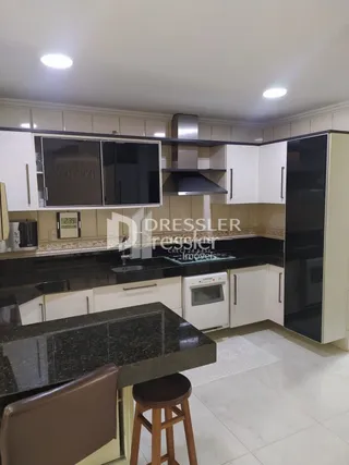 A imagem mostra o interior de uma sala com armários e bancadas escuras.