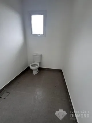 Vista de um corredor com um vaso sanitário em um imóvel.