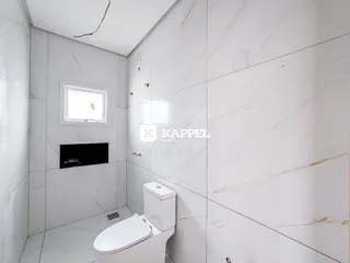 Banheiro com revestimento em mármore branco e louças brancas.